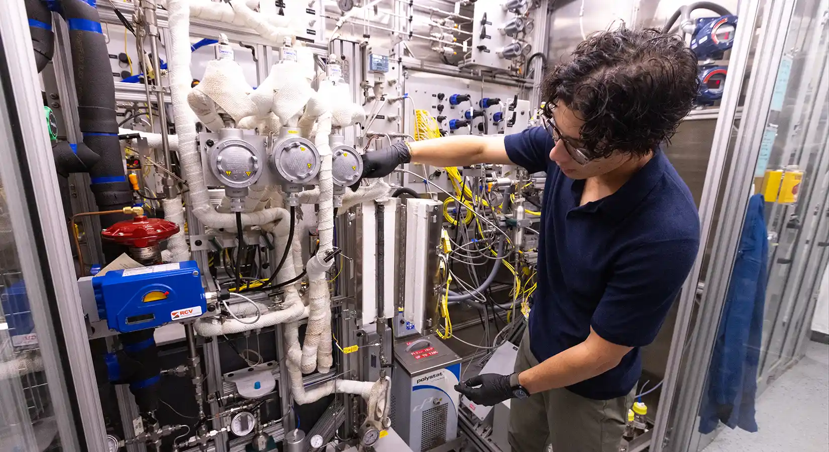 Researcher visually inspects a reactor in the Fuel Synthesis Catalysis Laboratory.