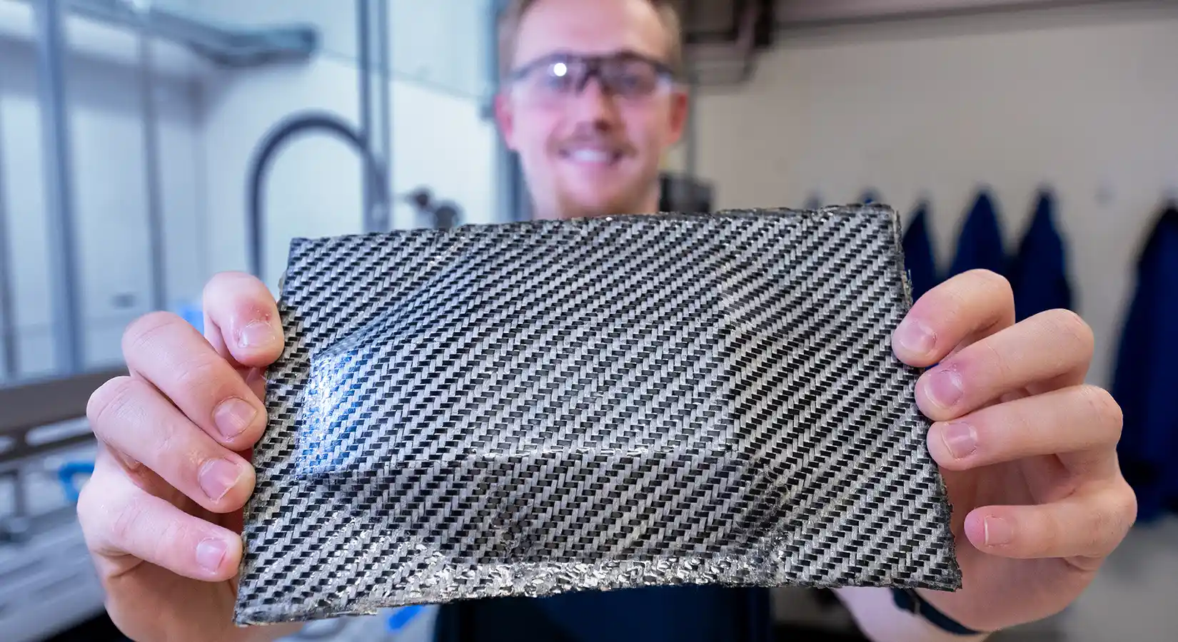 Researcher holds up a hybrid carbon fiber composite with enhanced ductility utilizing the PolyEster Covalently.