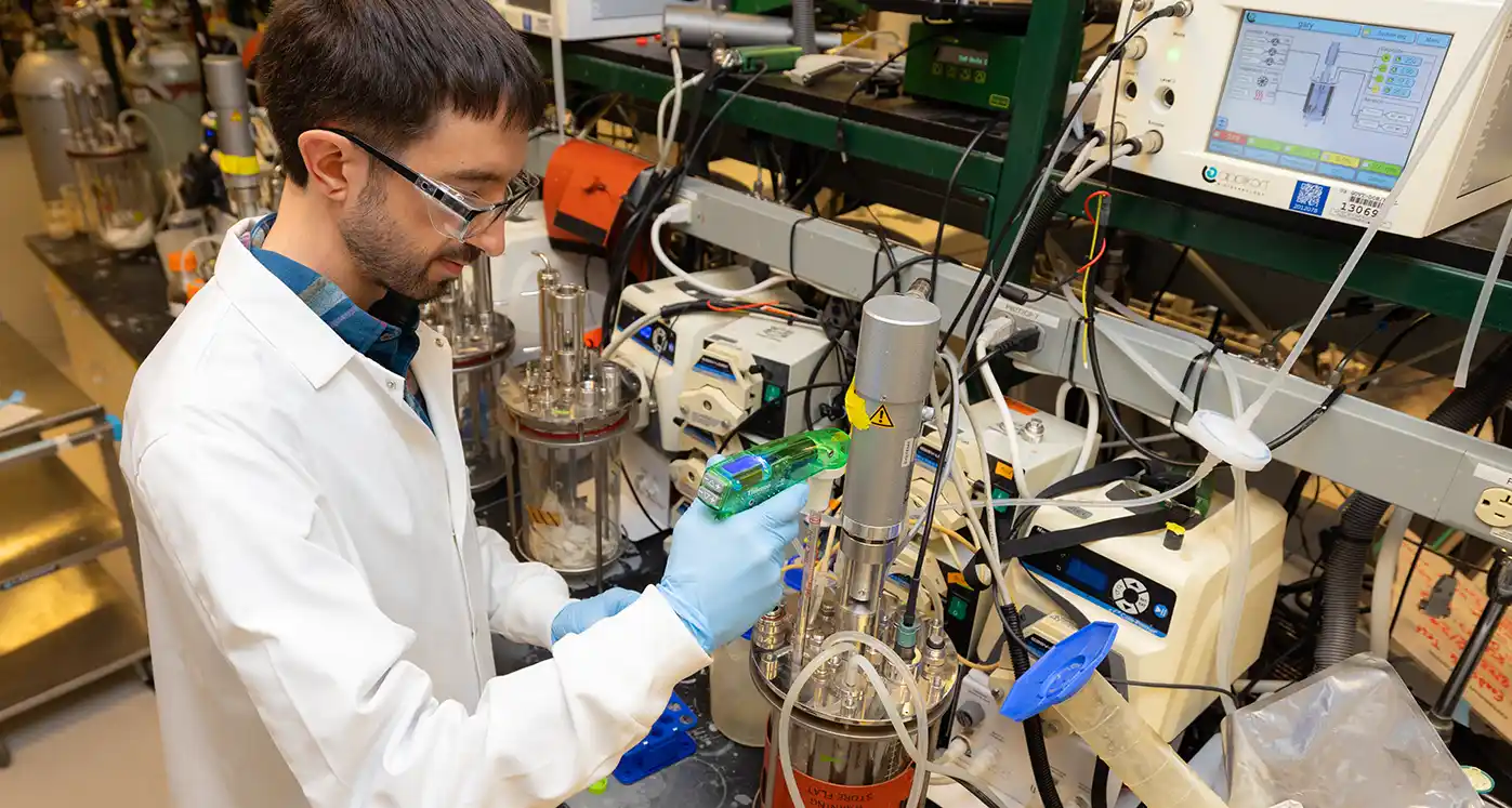 A biological science research technologist uses bioreactors and a hand-picked collection of unique enzymes to drive room temperature, controlled, and extremely precise reaction chains.