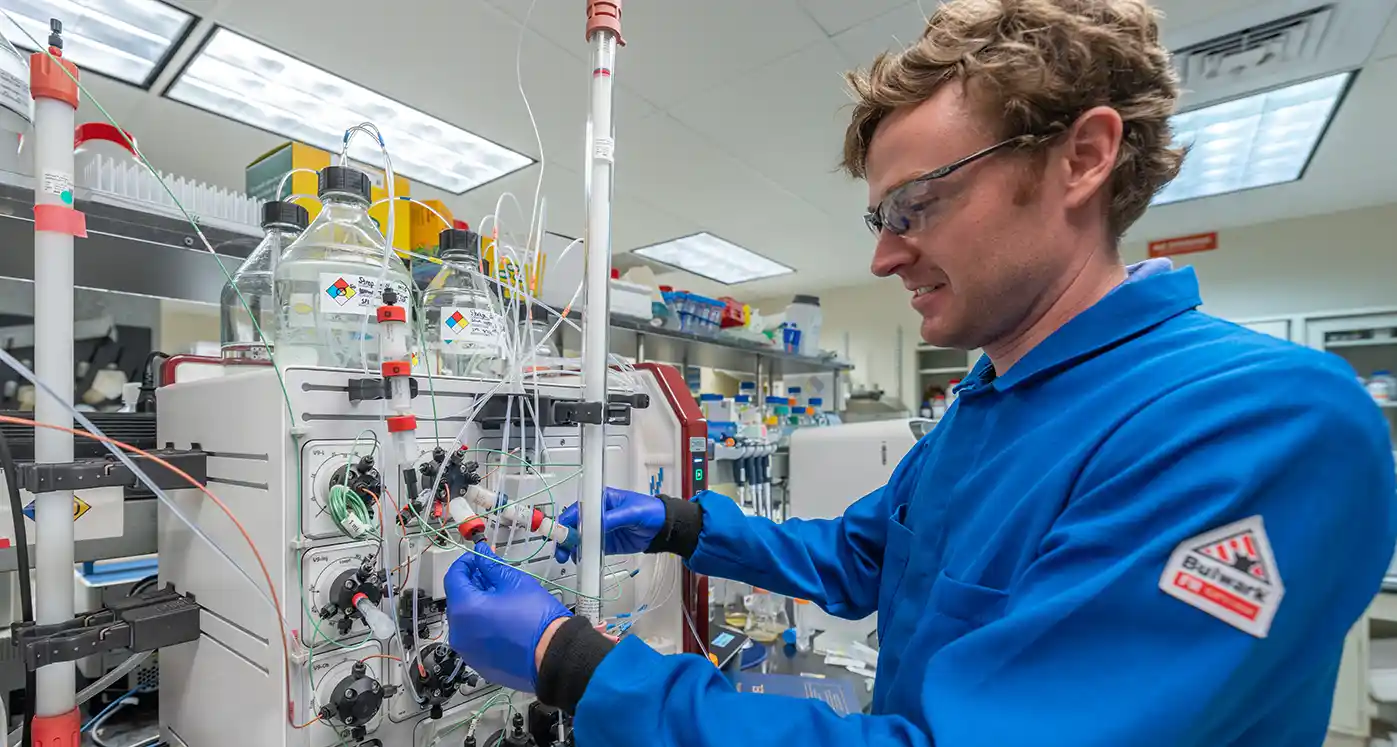Scientist collects a pure metal solution from an experiment on the pilot-scale multi-column chromatography system.