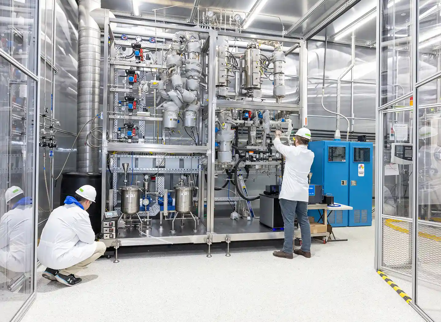 Two people wearing personal protective equipment working in a lab.