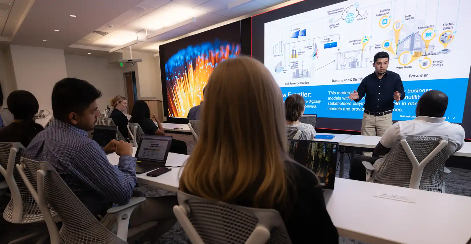 Researcher presents on cybersecurity project in front of audience in a room.