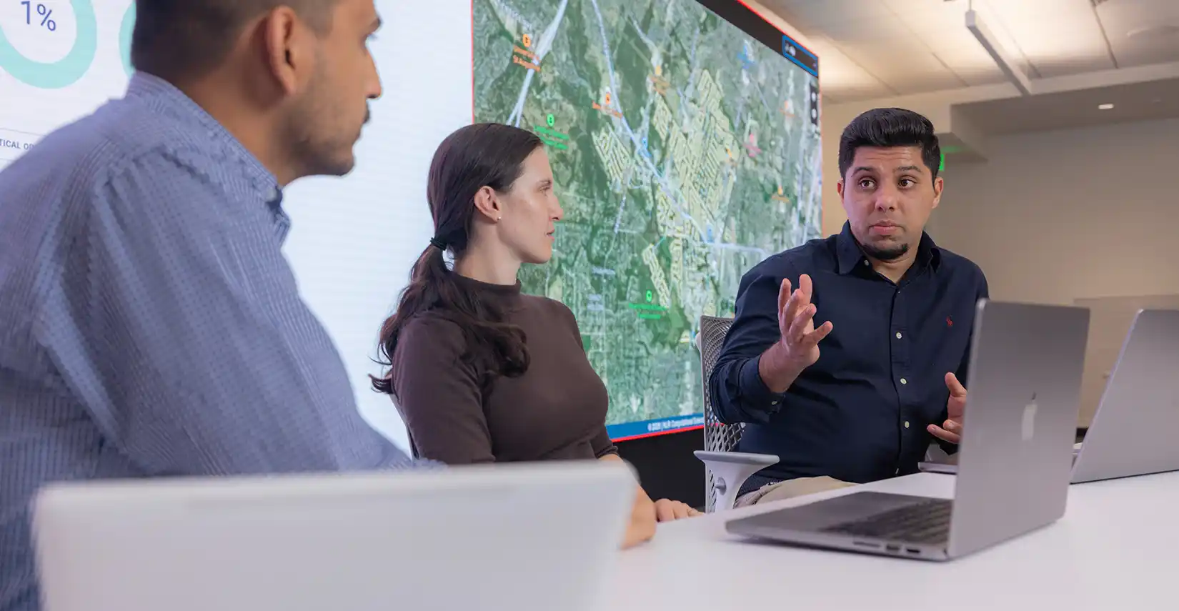 Three researchers have a discussion in front of laptops.