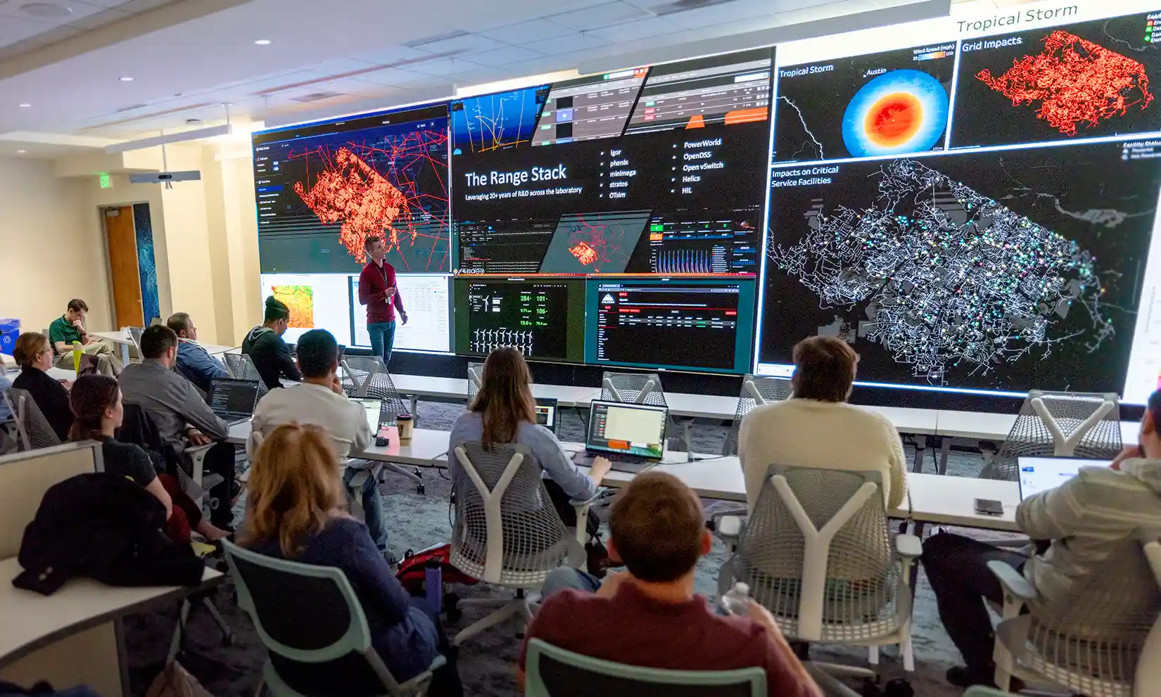 Large presentation screen with graphic and a seated audience.