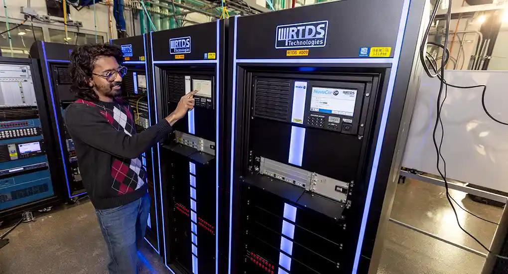 A man operates the control panel on electrical equipment.