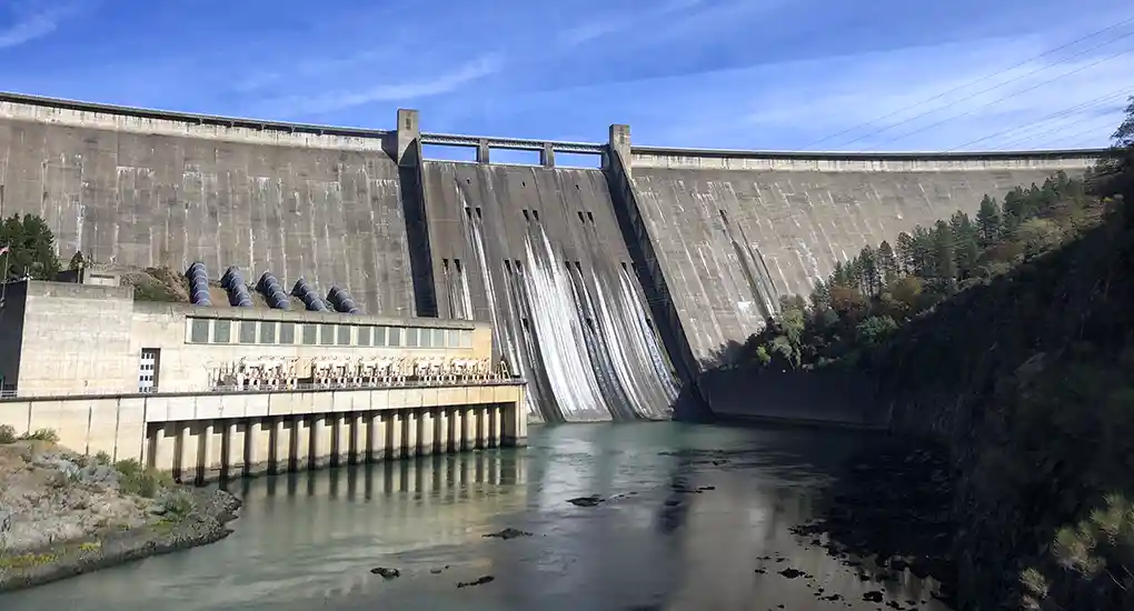 Water passes through a hydroelectric dam made of concrete.