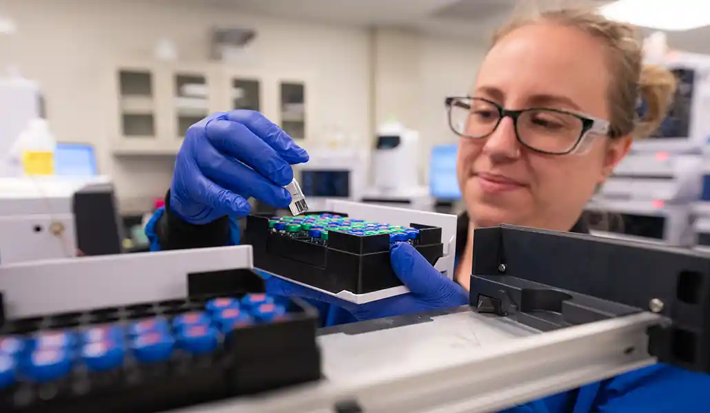 A research technician loads samples on an high-pressure liquid chromatograph.