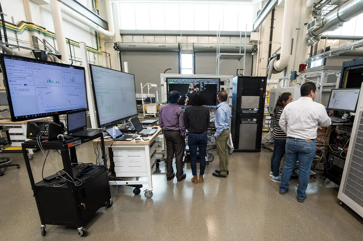 capability-adms-60101 Researchers in a lab looking at data on a large monitor.