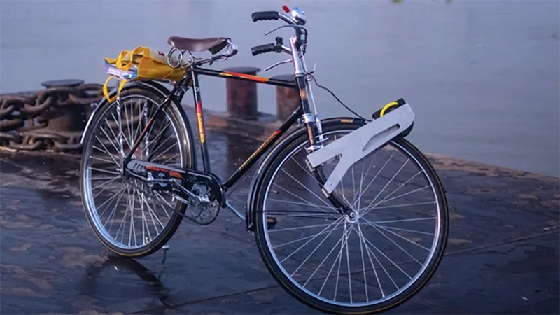 A black and red bicycle has a metallic device on its front wheel.