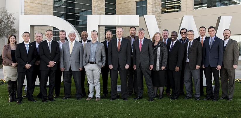 Photo of 20 people standing in front of a 