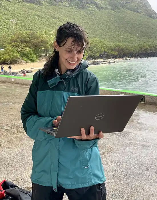 Excited researcher looking at her laptop on a beach.
