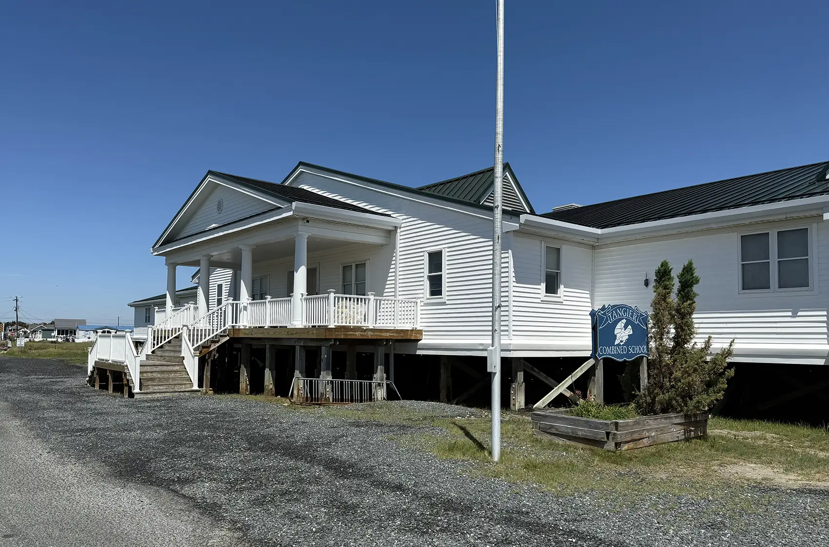 20260225-rising-above-the-tide-strategic-energy-planning-on-tangier-island-3240 A building with a sign in front of it that reads Tangier Combined School.