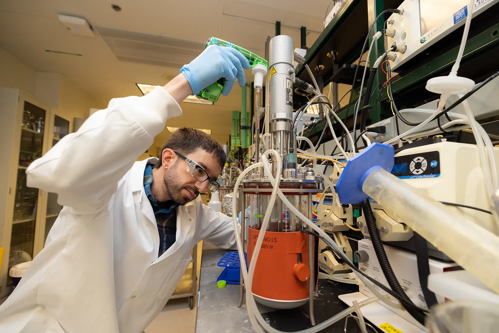 A researcher takes a sample from a bioreactor.