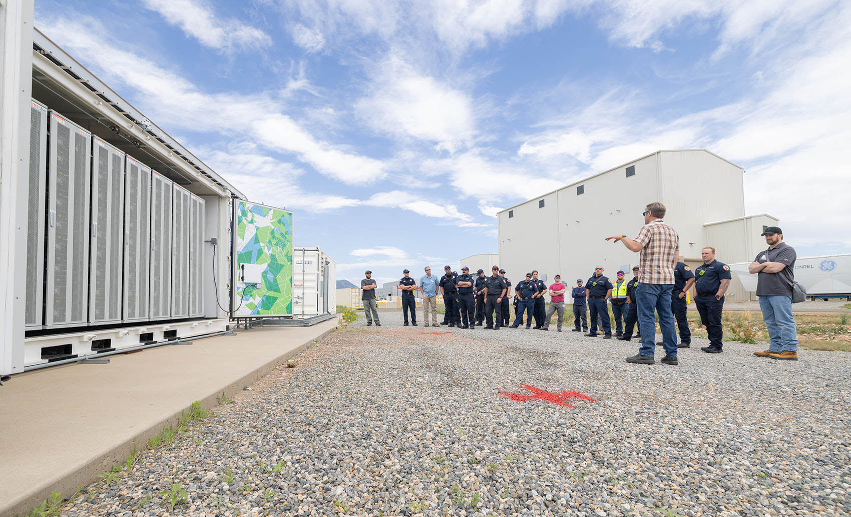 A large group of first responders standing next to a battery energy storage system.