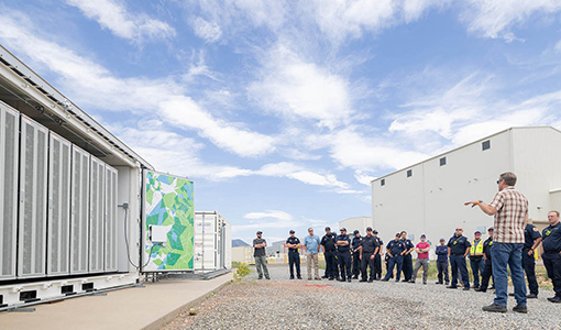 A group of first responders stand outside near a battery energy storage system.