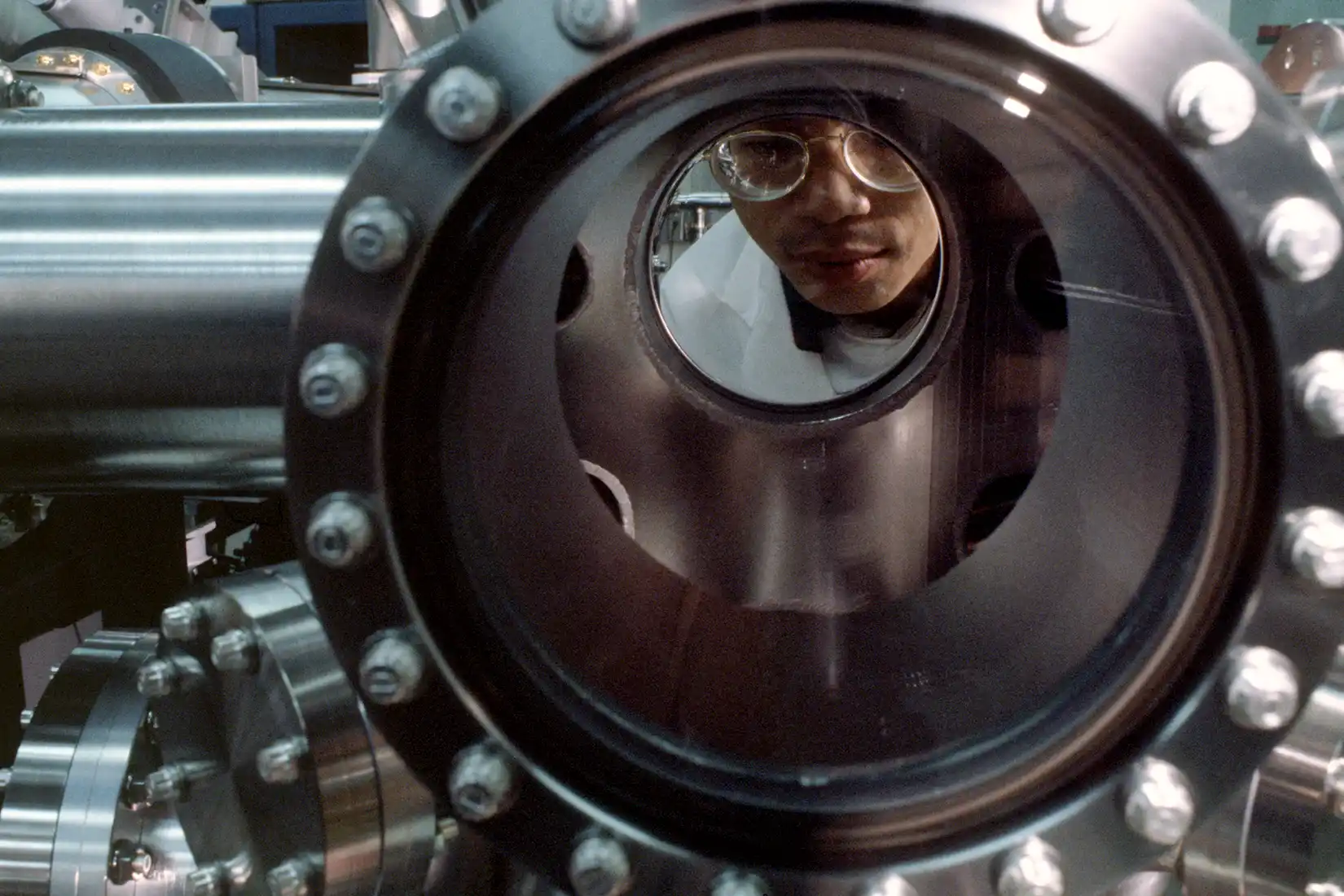 A researcher looks through a large metal tube.