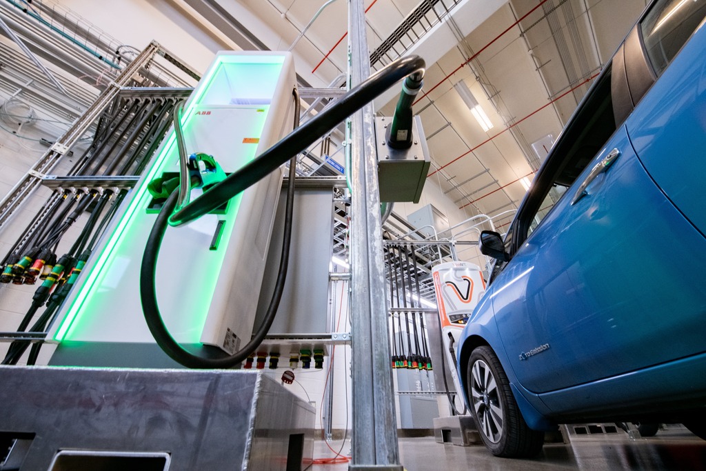 An electric vehicle positioned next to a fast charger. 