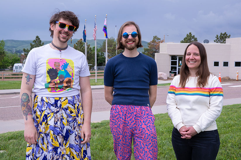 Three people standing in front of a flagpole. 