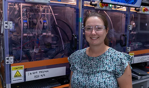Continue reading about A woman with safety goggles stands in front of electrolyzer testing equipment.
