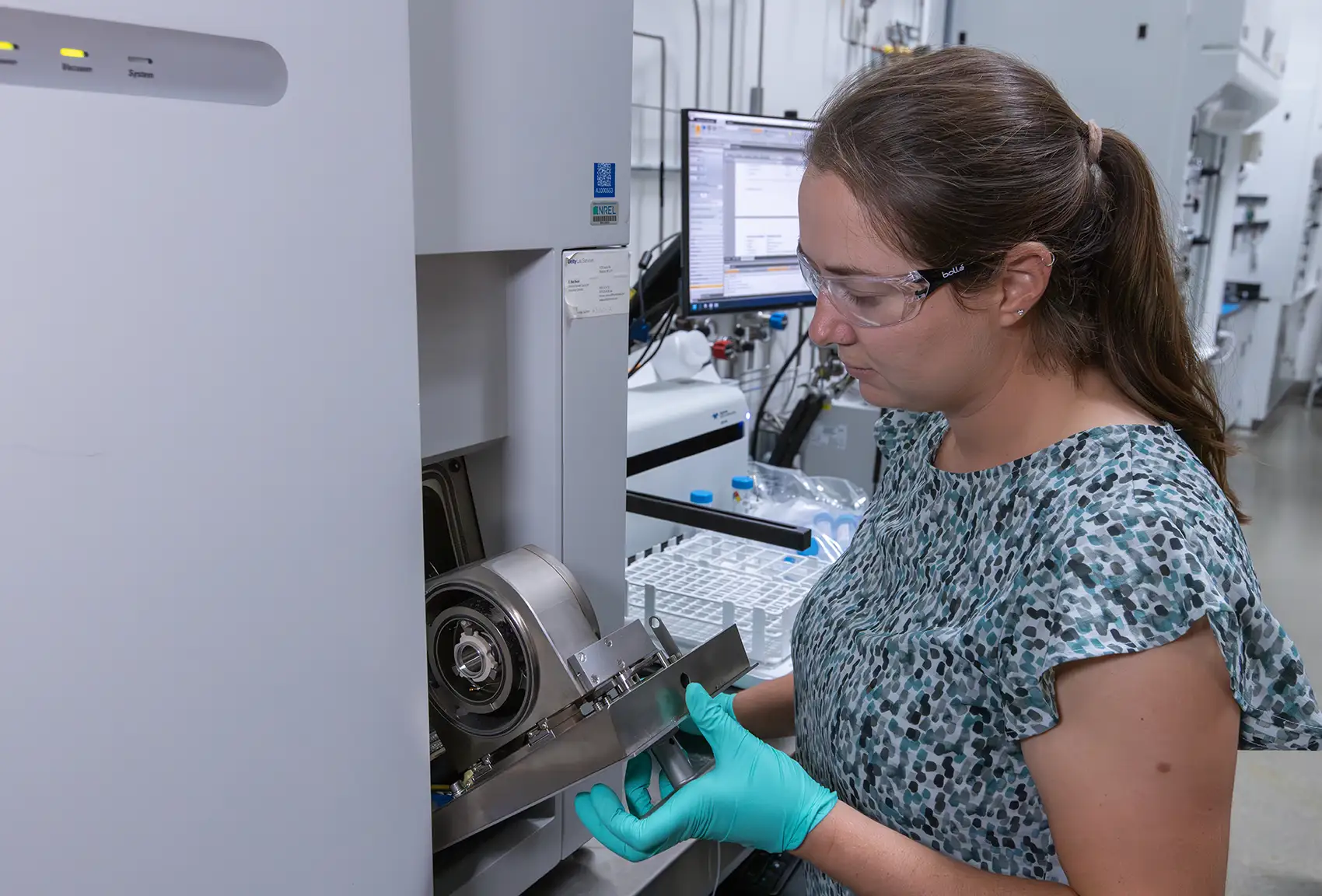 A woman with safety goggles interacts with electrolyzer testing equipment.