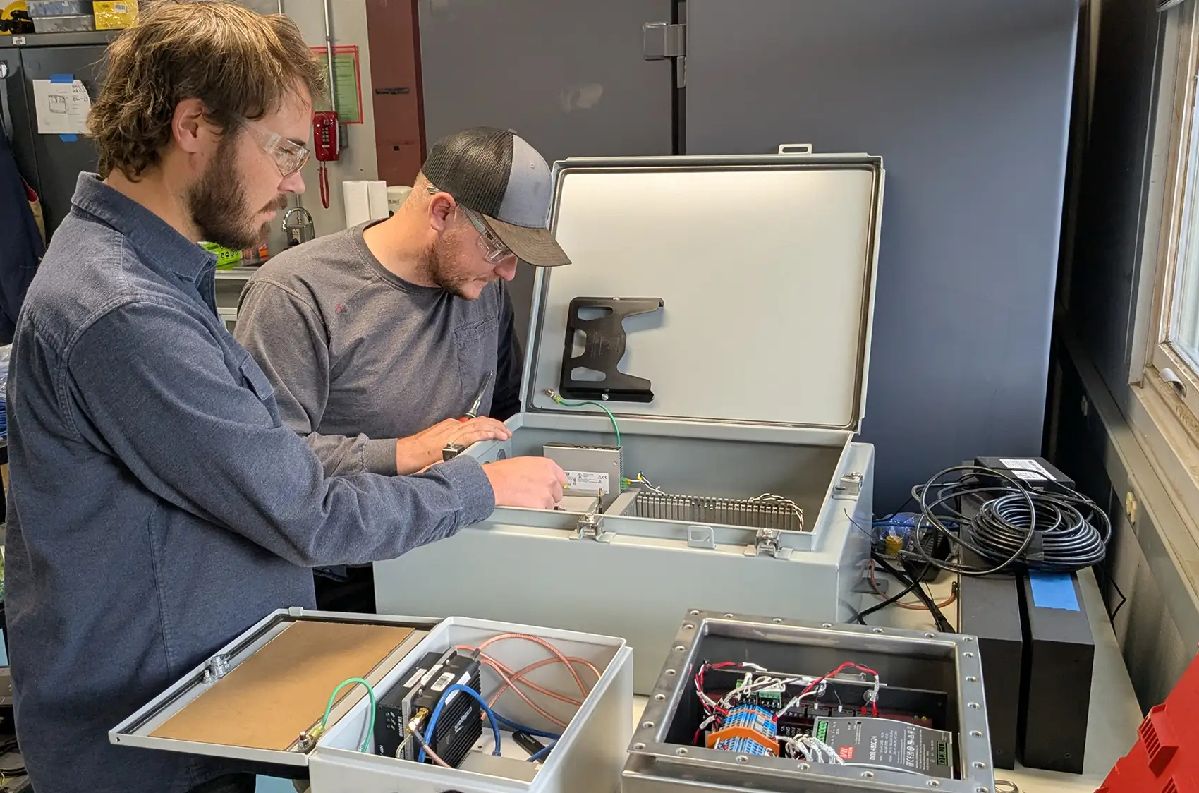 Two people look inside a box containing machinery.