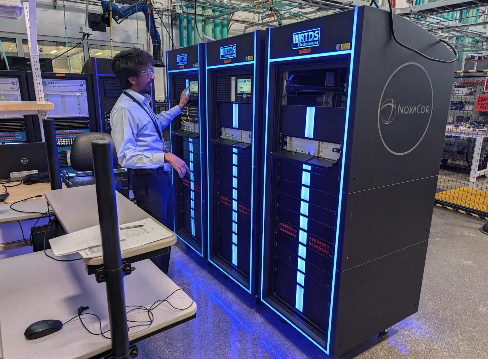 20260226-could-a-new-kind-of-data-center-give-back-to-grid-verrus-1 A person wearing safety goggles standing next to three server racks