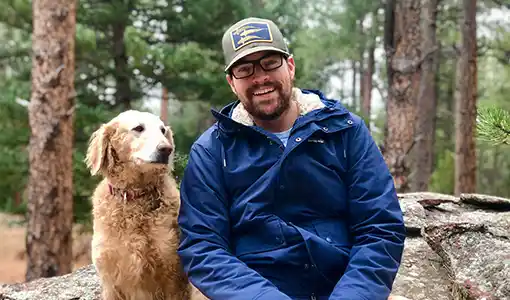 Continue reading about Trevor Martin hiking in the woods with his dog.
