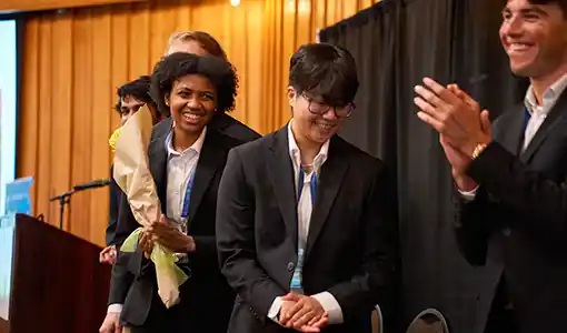Continue reading about Candid shot of five student competitors accepting an award on stage.
