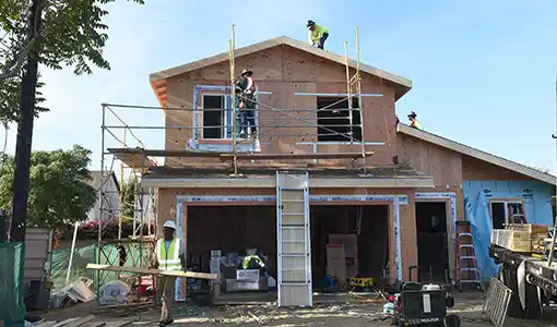 Continue reading about A home under construction with three men in hardhats working on different areas of the home.