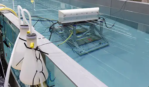 A wave tank in a laboratory showing the underwater testing apparatus inside the tank.