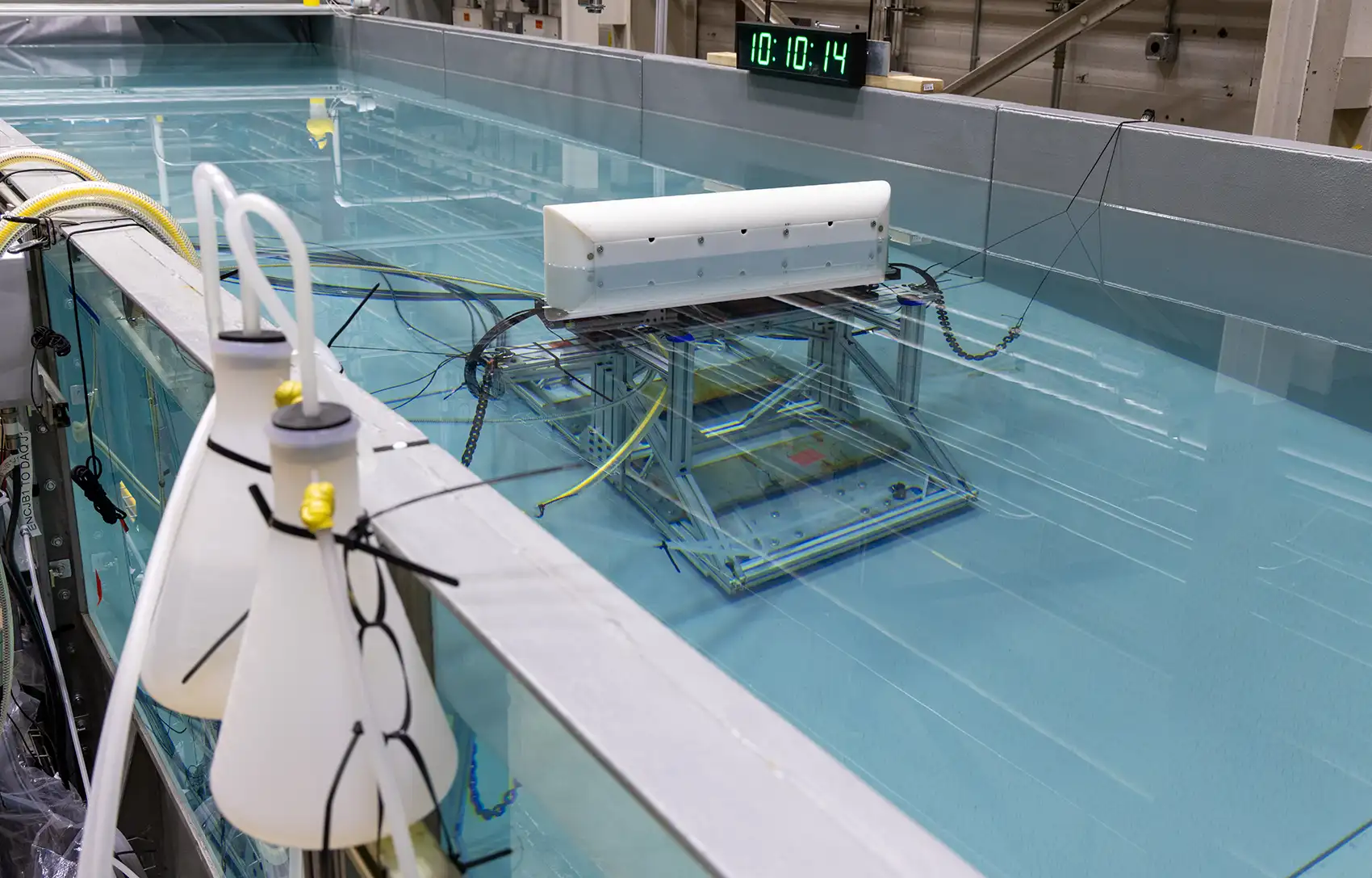 20260914-can-surge-wave-tech-survive-the-open-ocean-094232 A wave tank in a laboratory showing the underwater testing apparatus inside the tank.
