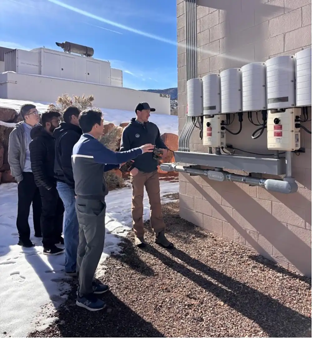 A group of people look at a transformer on a building.