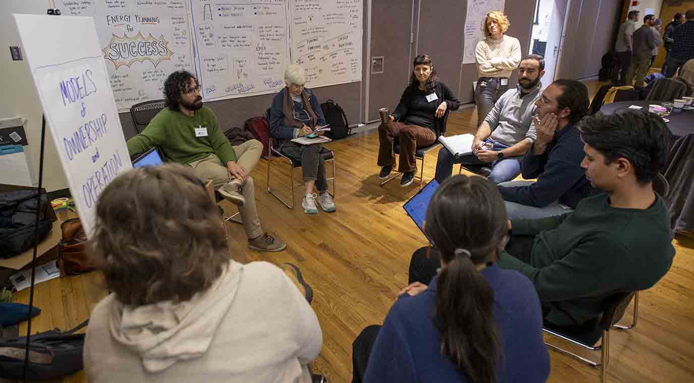 Group of people sit around and have a program discussion.