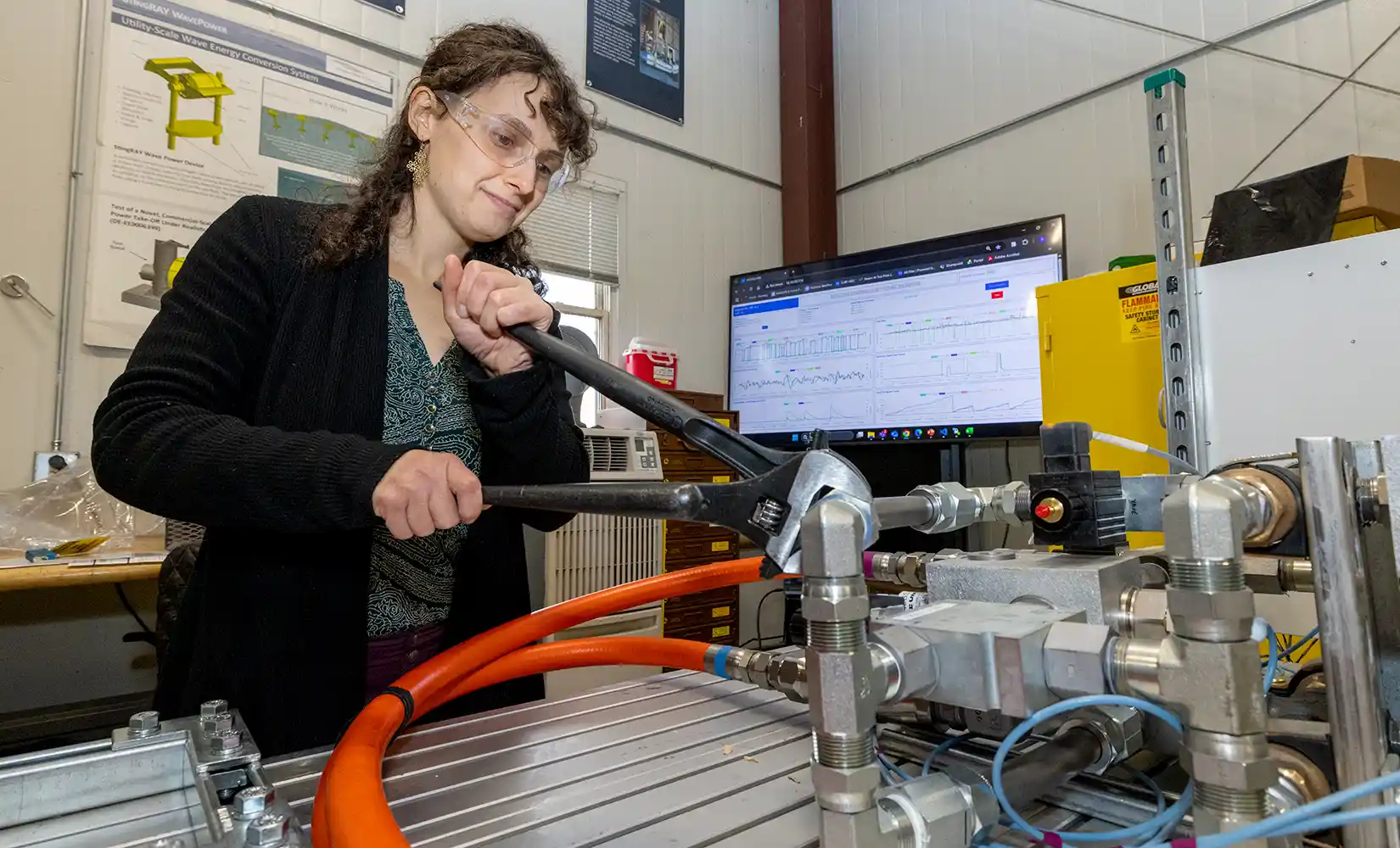 Researcher uses tool to adjust marine energy device inside the lab.