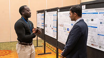 20240731-newsletter-nawi Researcher presenting a poster to a colleague at a NAWI event