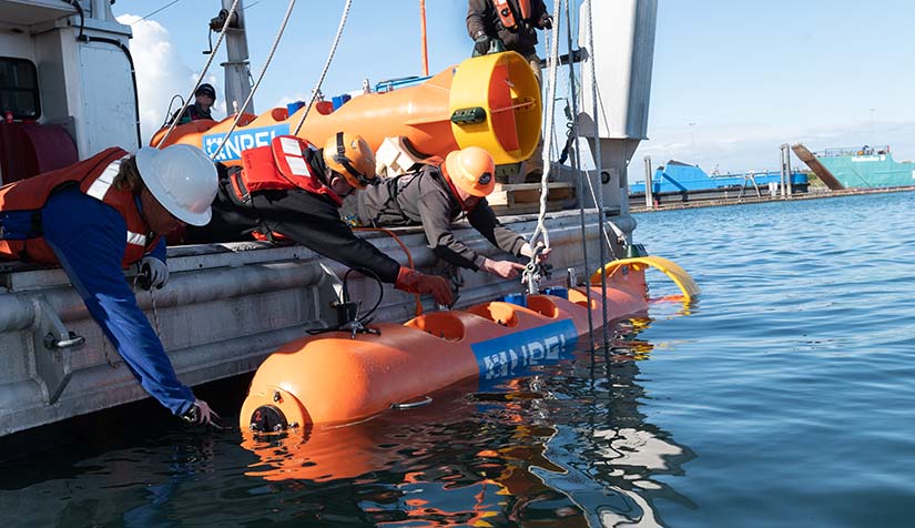 20240731-newsletter-tidal-energy Reserachers holding an NREL buoy steady while it is being unshackled for a ballast text in the Homer harbor in Alaska.