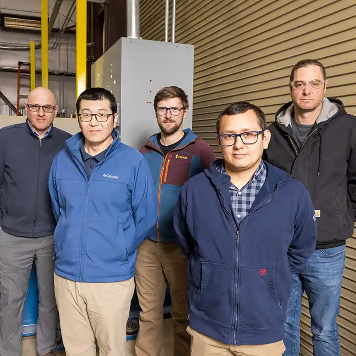 Five researchers stand for photo in hydropower laboratory