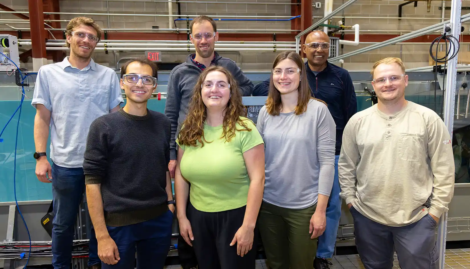 Group of researchers stand in front of wave tank.